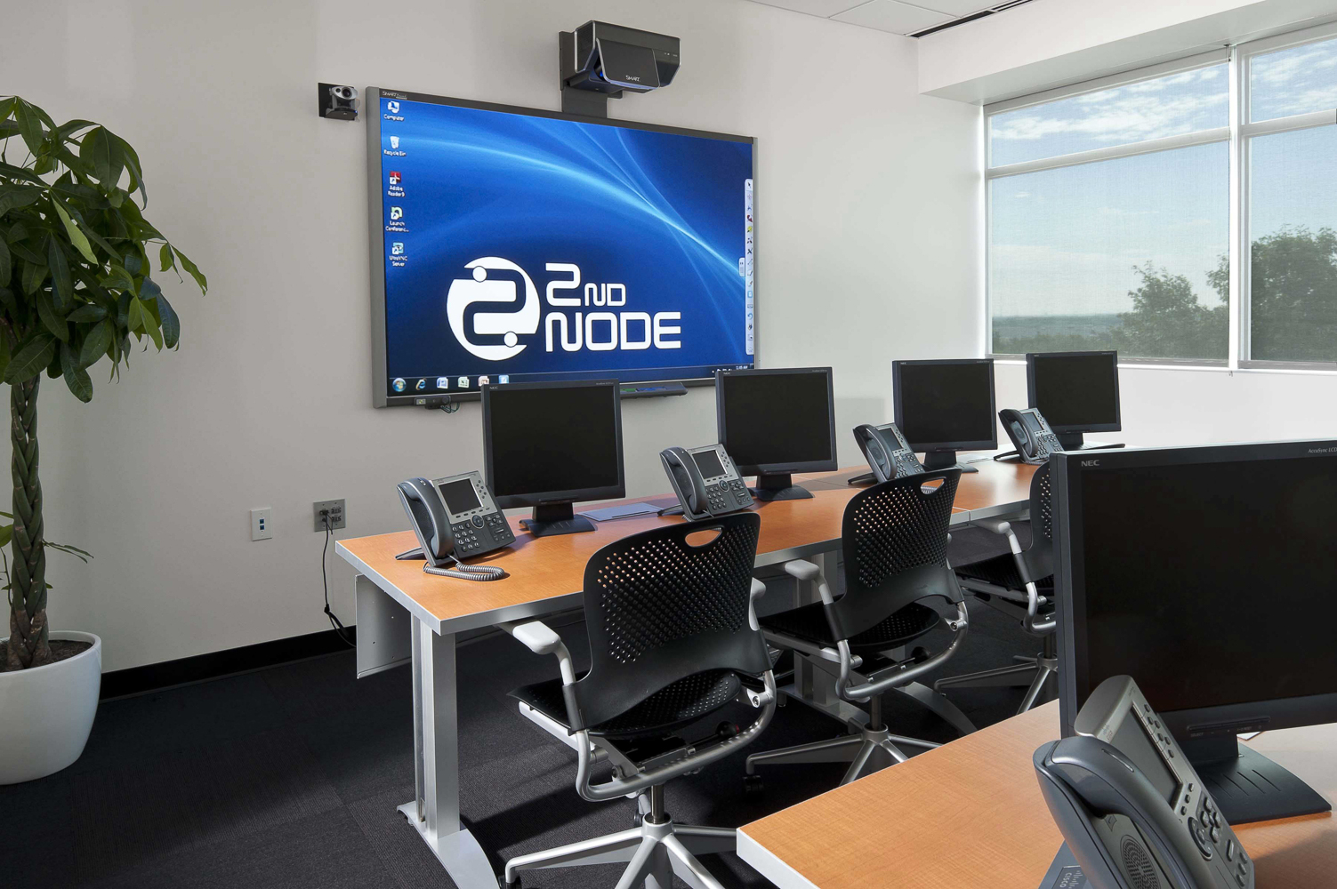 classroom with desks, chairs, and monitors facing a large screen
