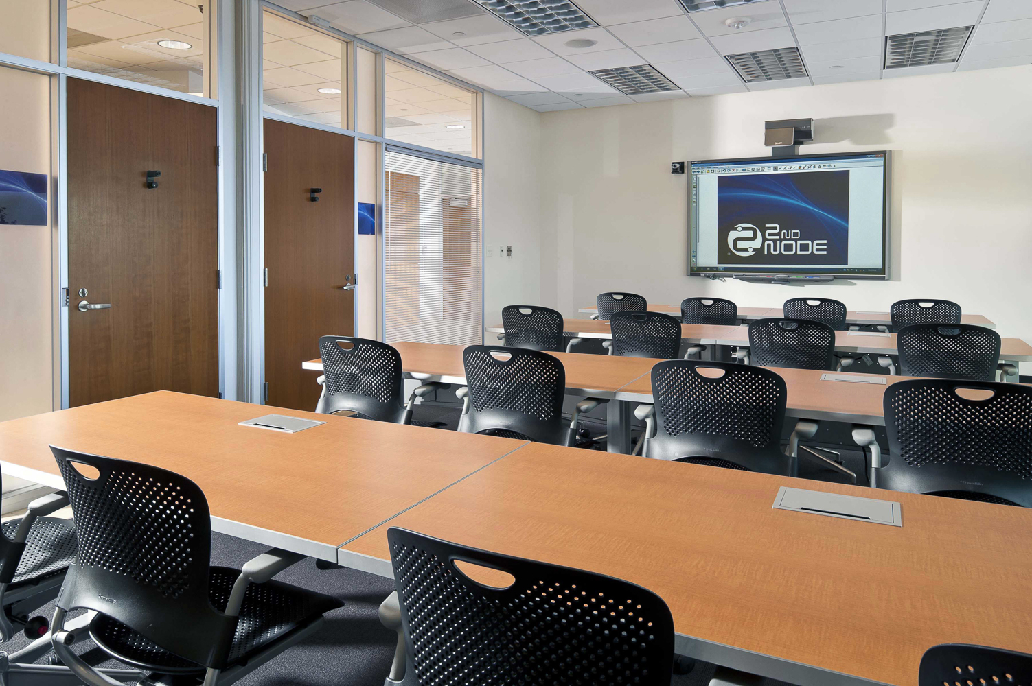 classroom with desks and chairs facing a large screen
